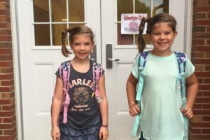 two girls with backpacks in front of school