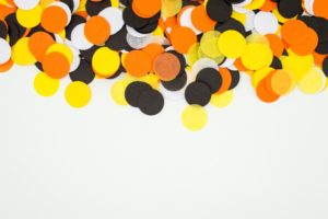 black, orange, yellow, and white confetti on a white tabletop for Halloween
