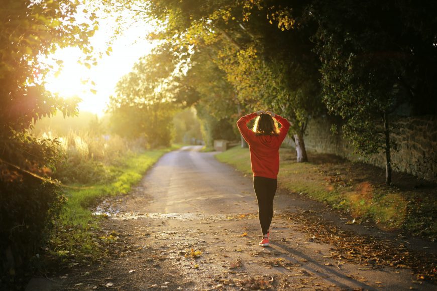 a woman walking down a dirt road as a way to fall into fitness