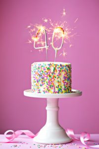 40th birthday cake with a sparkler candle on a pink background