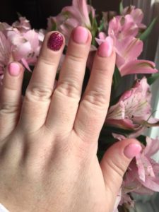 a woman's hand resting on flowers after dipping her nails with pink polishes