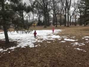 two children playing in a small patch of snow