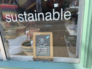 a storefront window that says sustainable and has woven baskets