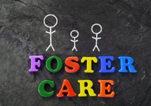 a stick figure family on a chalk board with letter magnets spelling out the words foster care