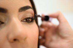 a close up of a woman putting on mascara