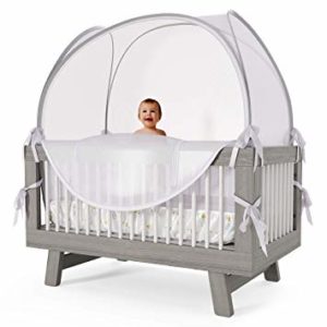 baby standing in crib with crib tent