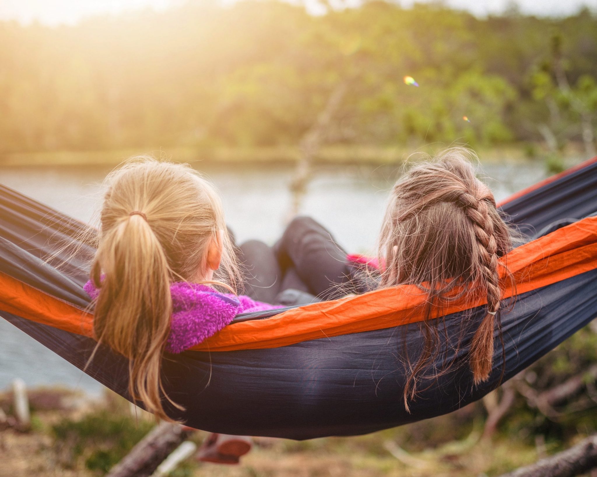 A hammock with two people with long hair sitting together
