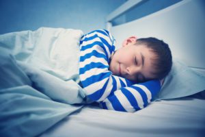boy in blue and white pajamas asleep in his bed