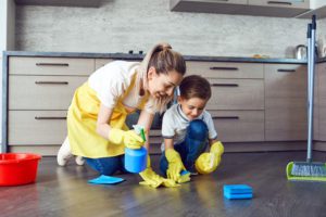 a mother and son using natural cleaning products to clean the floor