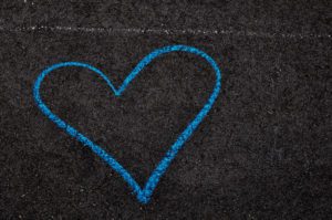 A blue sidewalk chalk heart on asphalt