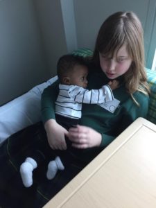 a caucasian girl holding on to her African American baby brother, reminding us that love is color blind