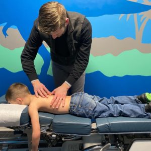 A boy laying on a chiropractor's table having his back adjusted.