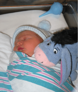 newborn baby boy in a hospital bassinet with a bulb syringe and an Eyesore stuffed animal