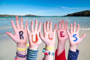Children Hands Building Colorful Word Rules. Ocean And Beach As Background
