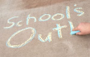 School's Out! written in yellow and blue chalk on cement
