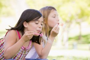 two girls blowing bubbles outside