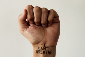 closeup of the raised fist of a man with the text I cant breathe on his wrist, as it is used as slogan in the George Floyd protests in response to police brutality and racism in the United States