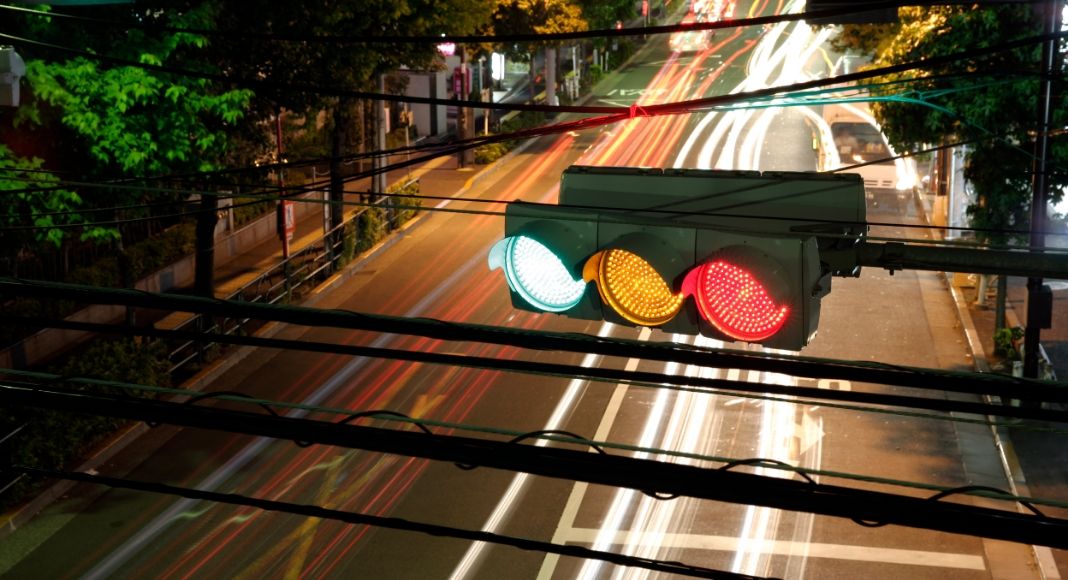 horizontal stop light at night with red, yellow, and green illuminated