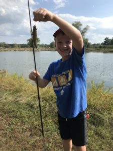boy holding fish caught while fishing in front of lake