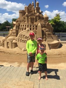 kids pose in front of giant sandcastle at The Magic House in St. Louis