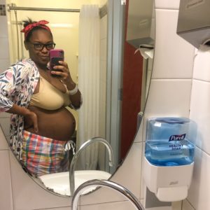 a new mom takes a photo of her postpartum body in the mirror at the hospital
