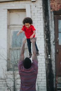 a black man lifting his son up in the air