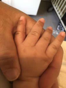 close up of a mom's hand holding her baby's hand