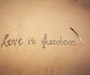 the words love is freedom written in the sand with a feather to symbolize love your body