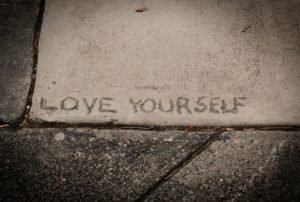 the words love yourself etched in a concrete sidewalk