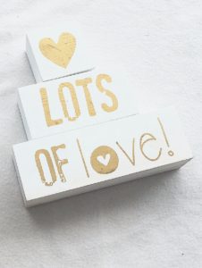 white pieces of wood with a heart and the words, "lots of love" painted on them in gold