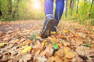 tennis shoe clad feet walking down a leaf strewn path
