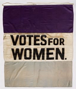 a banner with the words, Votes for Women as Kamala Harris runs as the first black woman for Vice President