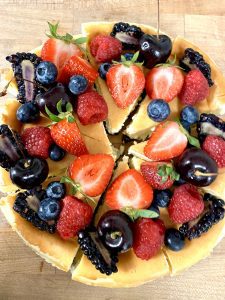 a close up of a cheesecake covered in strawberries and blueberries