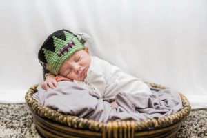 a photo of a newborn baby boy in a basket with a knitted Frankenstein cap as he was born on Friday the 13th
