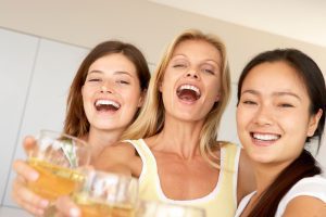 three moms standing together as the toast with their glasses of wine