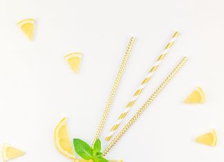 a lemon slice with straws stuck in it, with little lemon wedges in the background