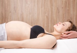 a pregnant woman laying on a table in a chiropractor's office as she gets her neck adjusted