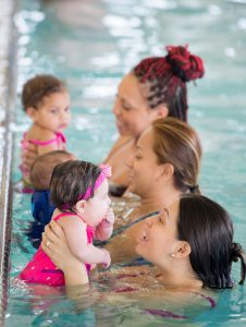 three moms with their babies in a mommy and me swim class