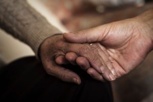 a young caregiver holding an older woman's hand