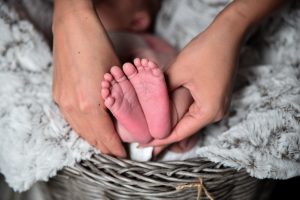 a close up of a mom holding her newborn baby's feet as he lay in a basket