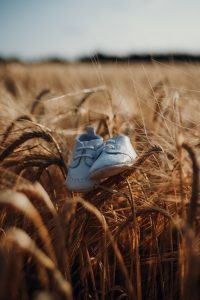 a close up of white baby shoes sitting on top of grass