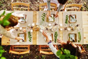 an outdoor table with cream colored placemats, sprigs of greenery, and place settings for a Thanksgiving meal
