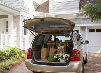 a minivan parked in a driveway with the trunk open and groceries in the back