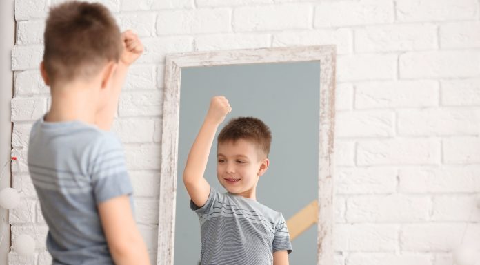 a young boy flexing his muscle as he looks into a mirror