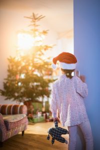 a young girl peeking around the corner at the Christmas tree on Christmas morning