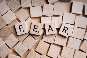 the word FEAR spelled out on scrabble tiles sitting atop a pile of blank tiles, representing an acronym to help you cope