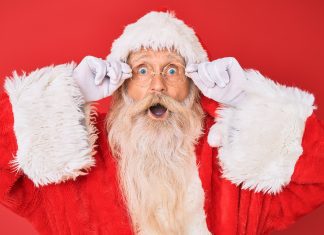 Santa Claus peering through his glasses with a surprised look on his face