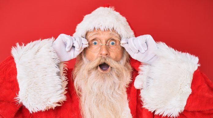 Santa Claus peering through his glasses with a surprised look on his face