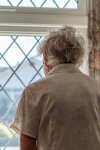 view from behind of an old woman looking out the window