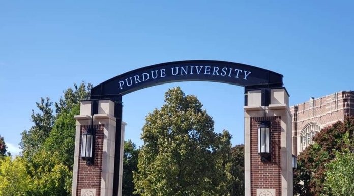 an archway on a college campus with a sign saying, "Purdue University"